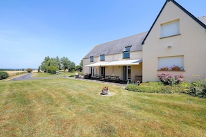 A two-story house with a covered porch, a lawn, and a view of the sea. - “Vol de mouettes” Guest Room with Shared Garden and Wi-Fi (Huisnes-sur-Mer)