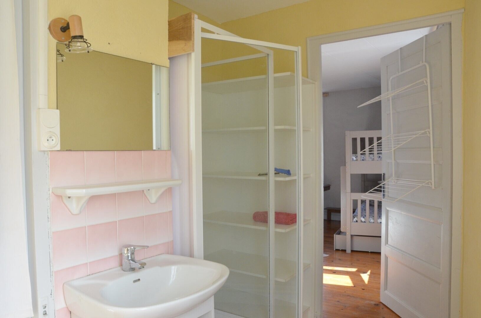Un bagno con lavandino, specchio e scaffalatura.