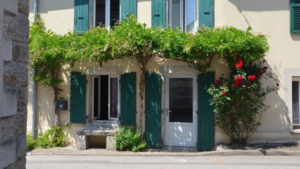 A building with a stone bench in front, green shutters, and a vine with red flowers. - Farmhouse Gîte - "La Popote" (Passenans)