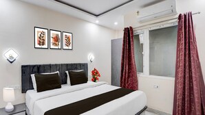Een hotelkamer met een bed, nachtkastjes, een wandairconditioner en een lijst met kunstwerk.