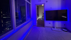 A room with a large window, a flat-screen TV, and a patterned carpet.