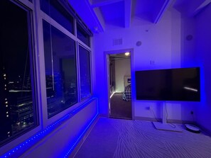 A room with a large window, a flat-screen TV, and a patterned carpet.