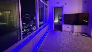 Una habitación con un ventanal grande, un televisor de pantalla plana y una alfombra estampada.
