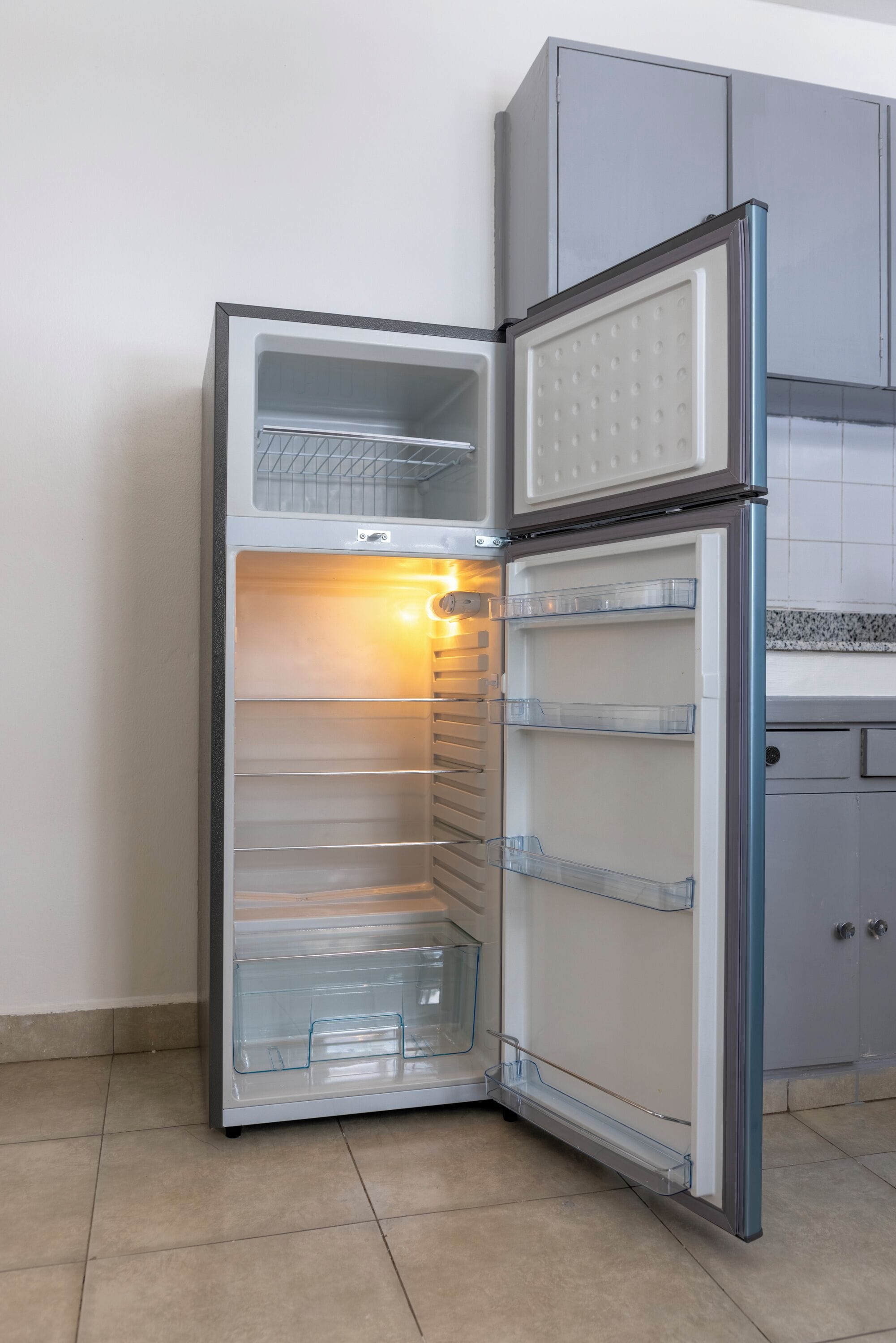 Eine moderne Küche mit Einbaukühlschrank, Fliesenboden und grauen Schränken.