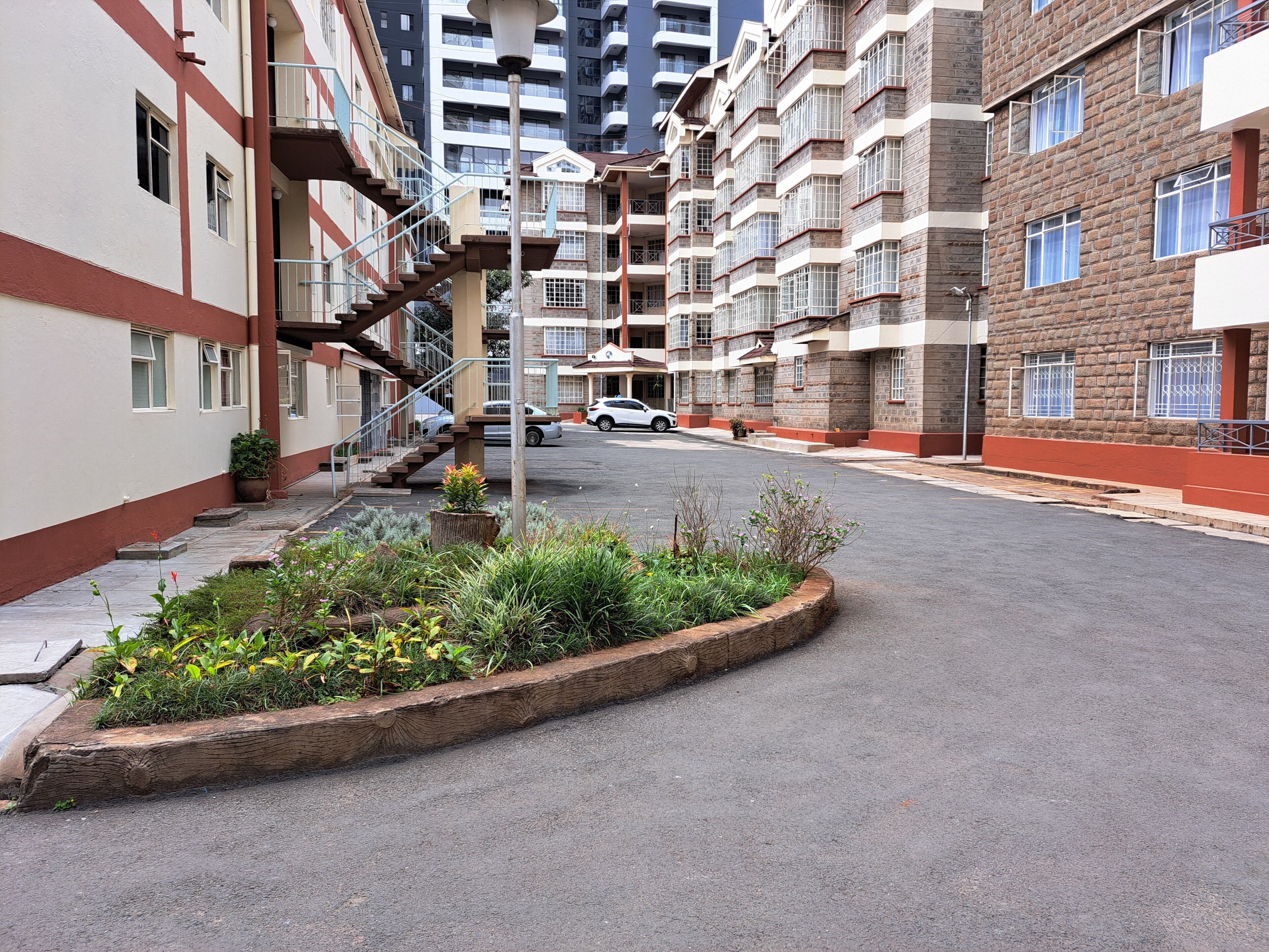 A residential area with multi-story buildings, a central garden, and a staircase leading to an upper floor.