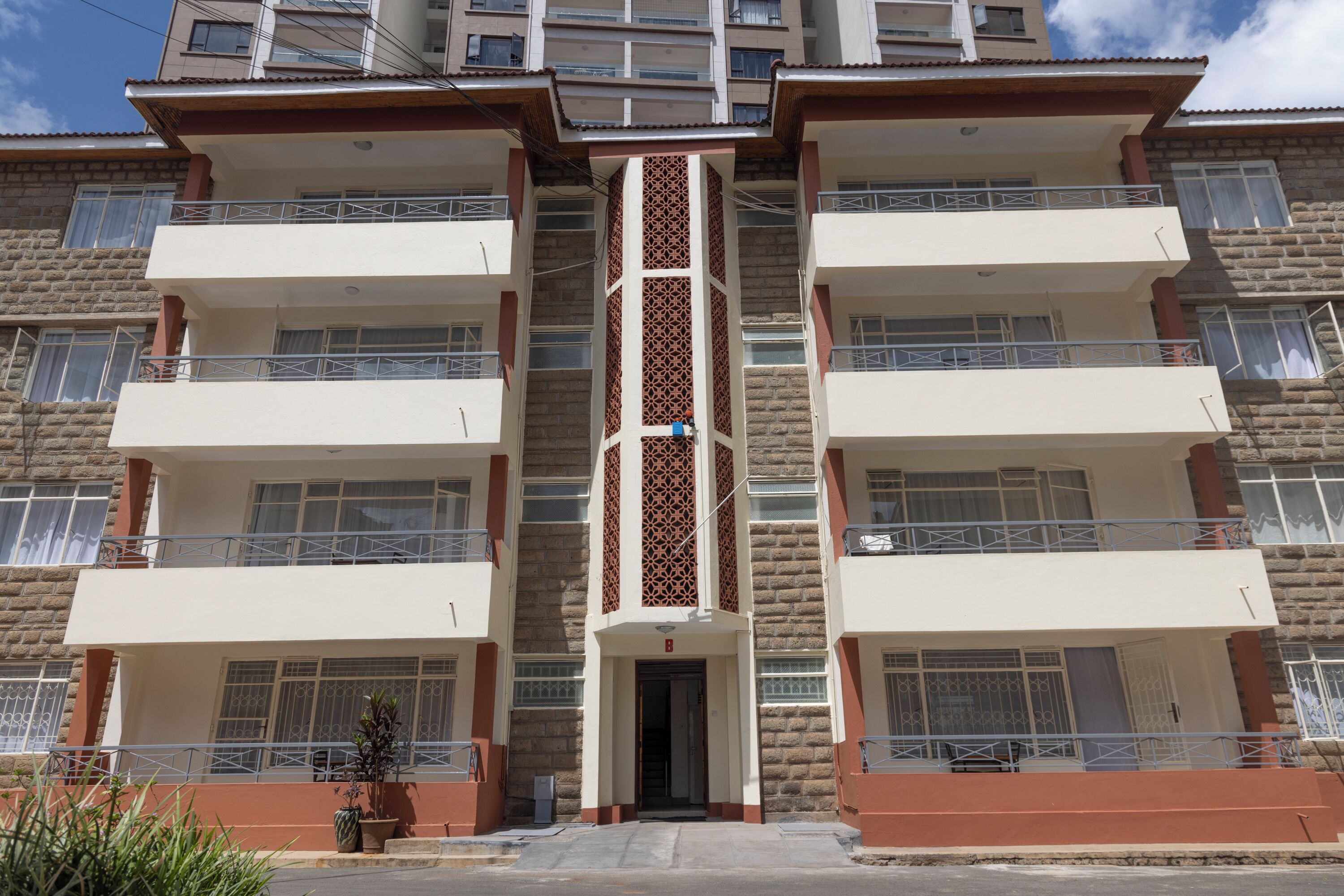 A multi-story residential building with balconies, a central entrance, and a patterned facade.
