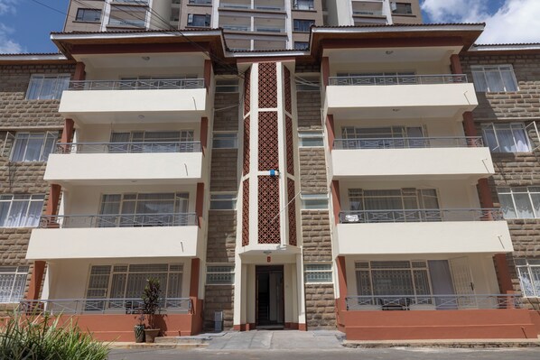 Un edificio residencial de varios pisos con balcones, una entrada central y fachada decorada.