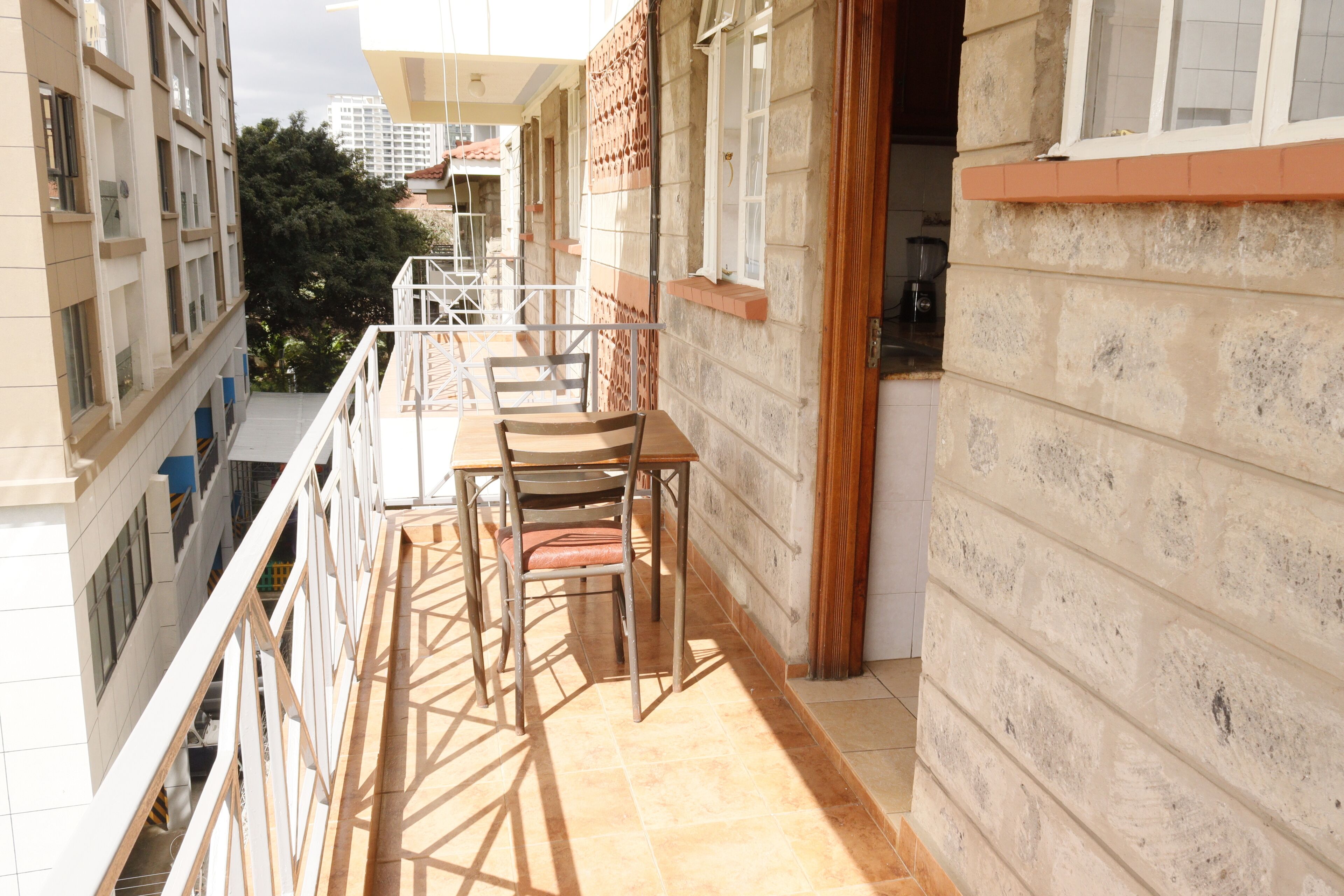 Un balcon avec une table et des chaises, une vue sur le paysage urbain et un immeuble à la façade en pierre.