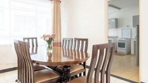 A dining area with a round table, six chairs, and a vase with flowers. - Gemina Court  (Nairobi)