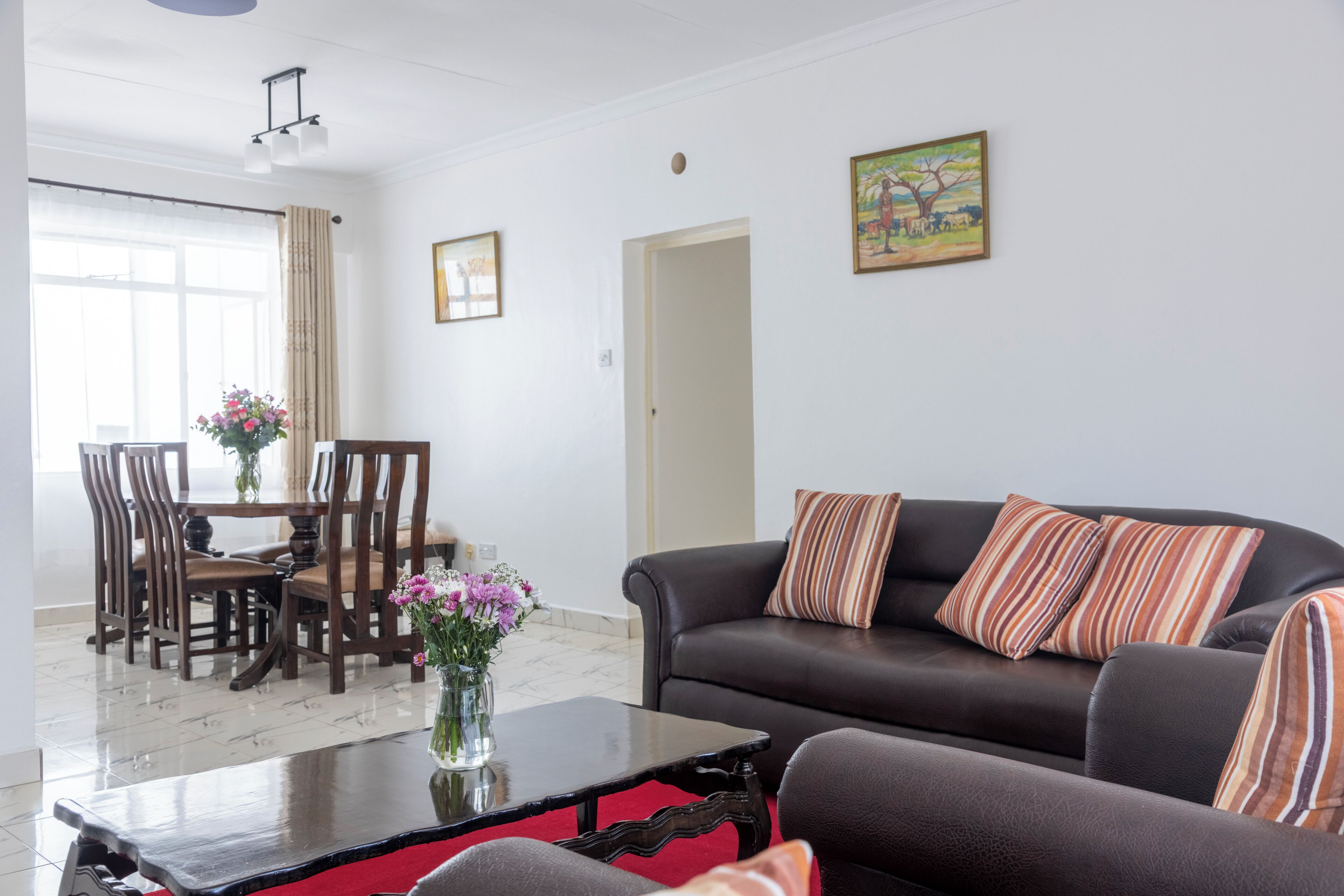 Een woonkamer met een bank, een salontafel en een eethoek met stoelen en een tafel.