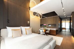 A modern hotel room with a large bed, a desk, and a kitchenette. - Native Apartments Wita Stwosza 24 (Kraków)