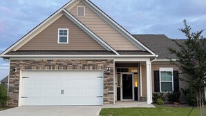A single-story house with a stone facade, a garage with two doors, and a front door with a glass panel.