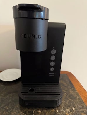 Een Keurig koffiezetapparaat met een zwarte basis en een transparante waterreservoir.