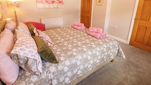 Una camera da letto con un letto, cuscini, un termosifone, un quadro e una porta.