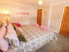 Ein Schlafzimmer mit Bett, Kissen, Heizkörper, einem Bild und einer Tür.