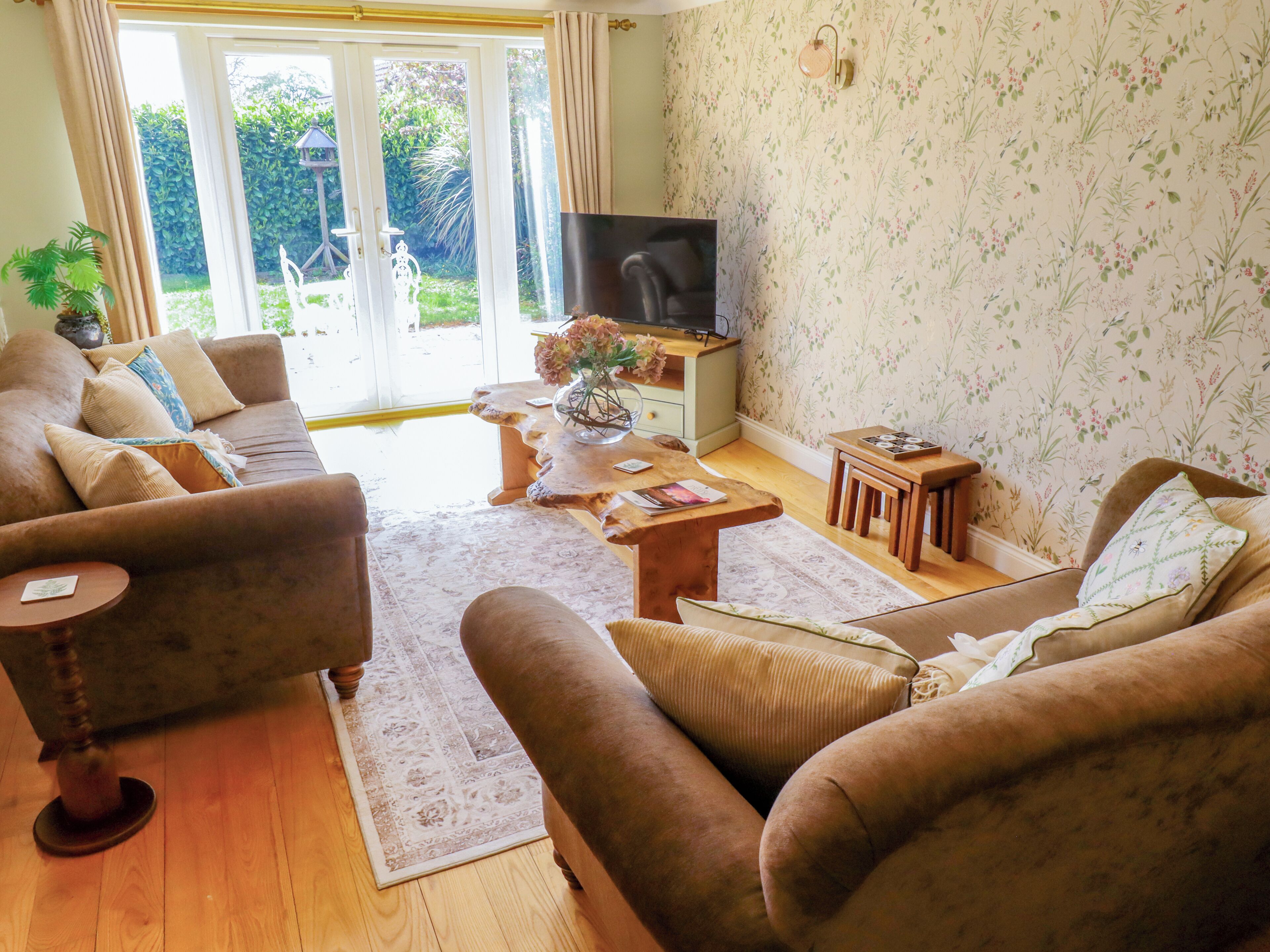 A living room with a sofa, a coffee table, a TV, and a patterned wall.