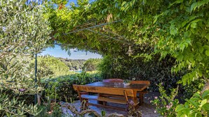 Un tavolo e una panca di legno in giardino, con vista su un lago.