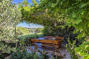 A wooden table and bench in a garden with a view of a lake. - Petra Sea View Apartment 5 (Kampor)