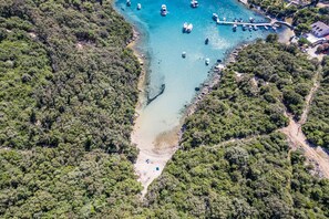 An aerial view of a coastal area with boats, a pier, and dense forest. - Petra Sea View Apartment 5 (Kampor)