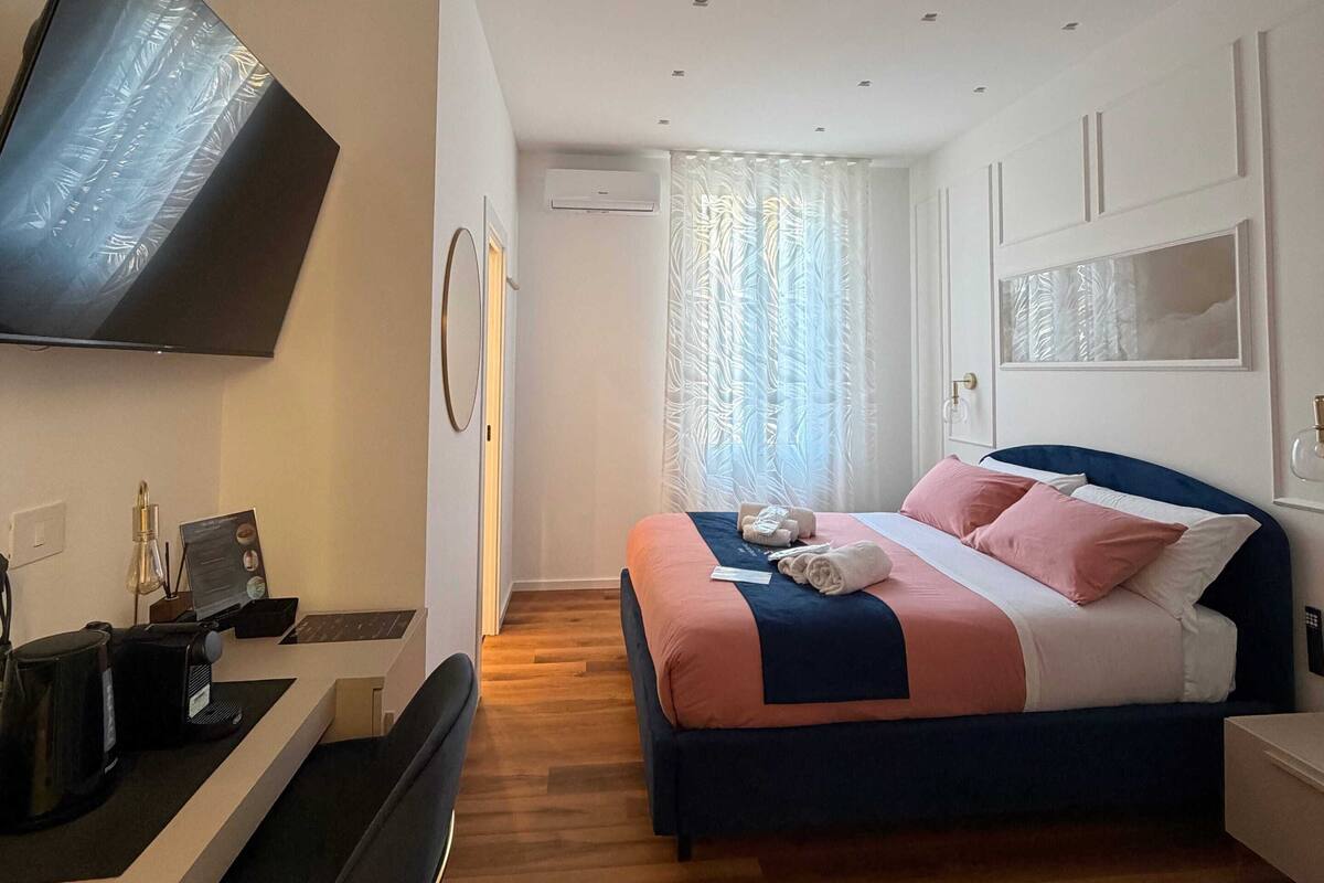A modern hotel room with a bed, desk, and flat-screen TV.