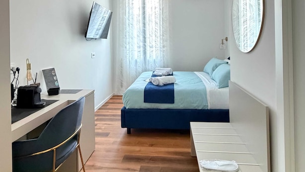 Een moderne hotelkamer met een bed, bureau, stoel en een aan de muur bevestigde televisie.