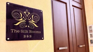 Een bordje voor 'The Silk Rooms B&B' aan een muur.