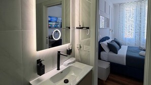 Een moderne badkamer met een grote spiegel, een witte wastafel en een douchecabine.