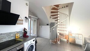 Eine Küche mit Waschmaschine, Mikrowelle und einer Wendeltreppe zu einem Schlafzimmer im oberen Bereich.