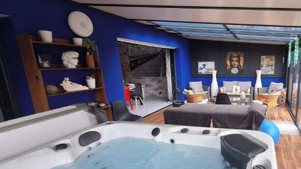 A spa area with a hot tub, seating, and a staircase leading to an upper level. - A l'ombre des 2 tilleuls (Sainte-Pazanne)