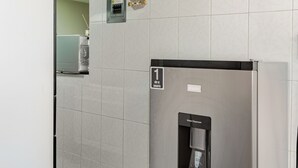 Una cocina moderna con un refrigerador de acero inoxidable, un dispensador de agua y un pequeño cuadro eléctrico en la pared.
