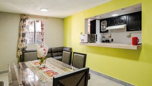 Un comedor con mesa, sillas y una cocina equipada con armarios y electrodomésticos.