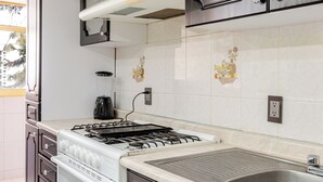 Una cocina con armarios oscuros, una estufa blanca y un salpicadero de vidrio.