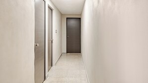Un pasillo estrecho con dos puertas, una de ellas abierta y otra cerrada al final.