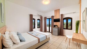 A hotel room with a bed, a desk, a TV, and a view of the outdoors. - Welcome Apts laid just 1600m away from the longest sandy beach of northern Crete and the touristic Georgioupolis Town, offering great views to the Cretan Sea and the White Mountains.  Welcome Apts is ideal for couples, families, a group of families or a g (Exopoli)
