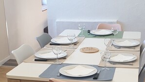 Ein Esstisch mit Tellern, Gläsern und Besteck, umgeben von Stühlen.