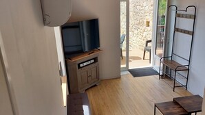 Ein modernes Wohnzimmer mit Flachbildfernseher, Holzboden, einer Couch und einem Essbereich mit einer Bank.