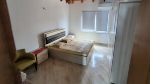 Une chambre avec un plafond en bois, un lit, une table de chevet, une chaise et une fenêtre.
