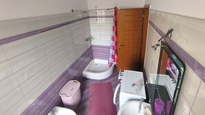 Une petite salle de bain avec une douche, des toilettes, un lavabo et un miroir.