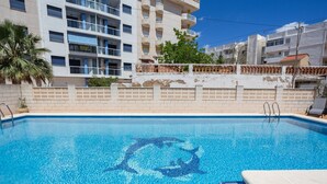 A swimming pool with a dolphin mosaic, a white building with balconies, and a palm tree. - Holiday Home 'Villa Miramar Beach' with Mountain View, Wi-Fi and Air Conditioning (Miramar)