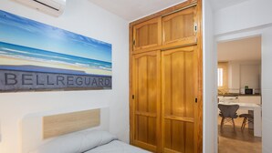 A bedroom with a bed, a wooden wardrobe, and a painting of a beach. - Holiday Home 'Villa Miramar Beach' with Mountain View, Wi-Fi and Air Conditioning (Miramar)