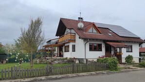 Ein zweistöckiges Haus mit Balkon, Satellitenschüssel und Solaranlage auf dem Dach.