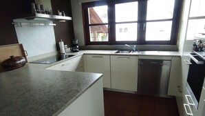 Eine Küche mit weißen Schränken, einer Granit Arbeitsplatte, einer Kaffeemaschine und einem Fenster mit Blick ins Freie.