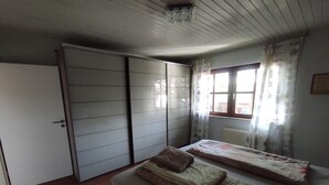 Ein Schlafzimmer mit einem Bett, einem Kleiderschrank und einem Fenster mit Vorhängen.