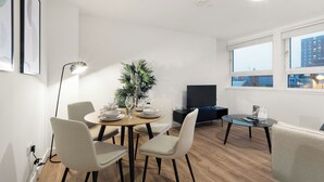A modern living room with a dining area, a flat-screen TV, and large windows with a city view. - City Point Aberdeen by Guestz (Aberdeen)