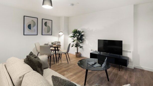 A modern living room with a sofa, a dining table with chairs, a TV on a stand, and a potted plant. - City Point Aberdeen by Guestz (Aberdeen)