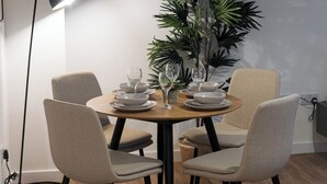 A dining area with a round table, four chairs, a floor lamp, and a large potted plant. - City Point Aberdeen by Guestz (Aberdeen)