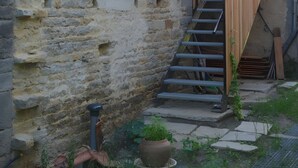 A stone building with a wooden staircase leading to a second floor. - Farm Cottage - "Le Perchoir" (Passenans)