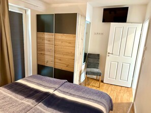 Un dormitorio con cama, armario, silla y televisor.