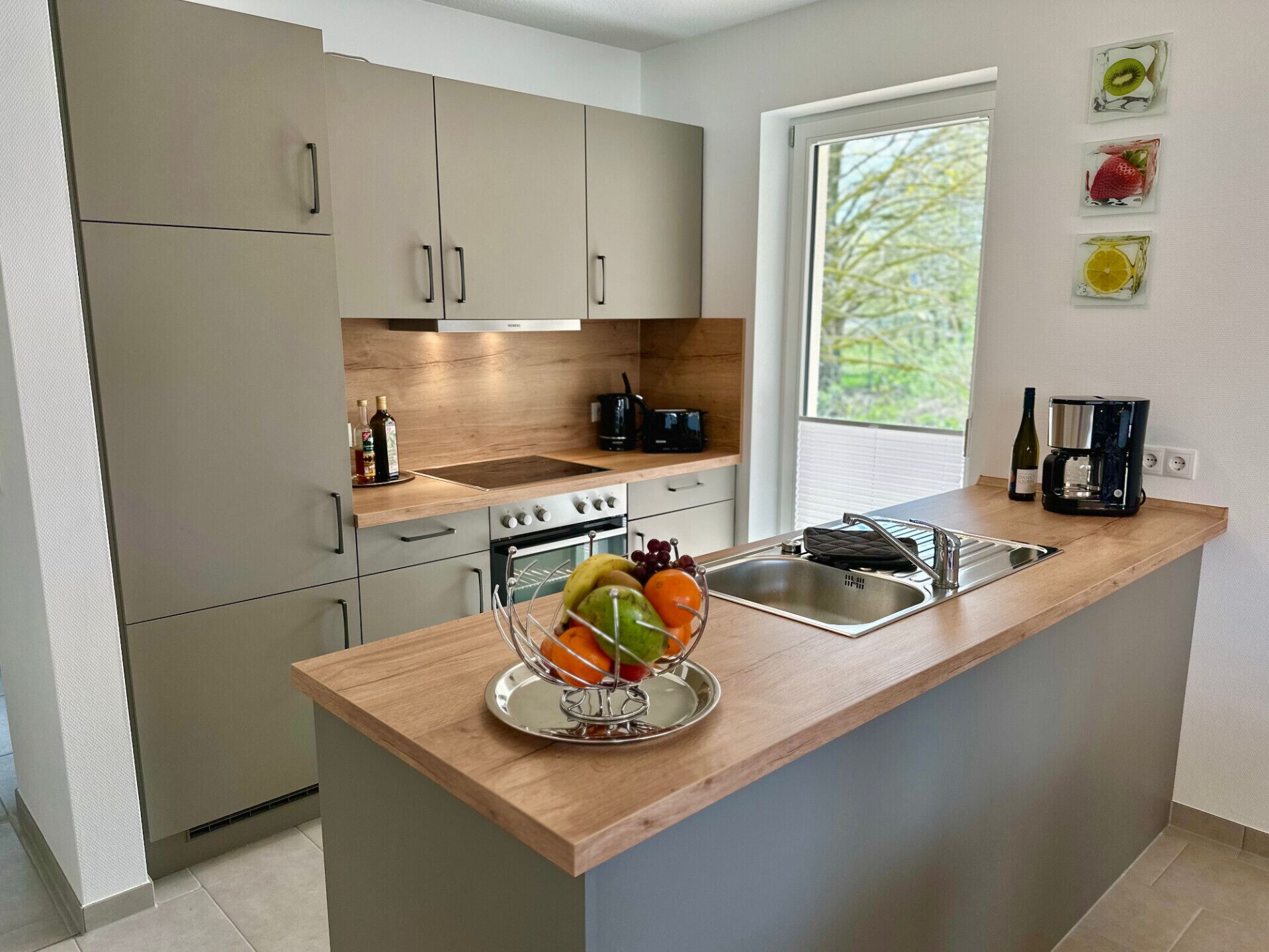 A modern kitchen with a wooden countertop, stainless steel sink, and a built-in oven.