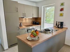 Una cocina moderna con encimera de madera, pileta de acero inoxidable y horno empotrado.